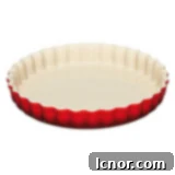 A high-quality Le Creuset ceramic quiche pan, essential for even baking and beautiful presentation.