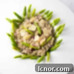 Close-up of a serving of creamy Wild Asparagus Risotto garnished with fresh asparagus spears and Parmesan cheese.