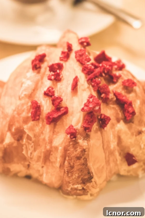 croissant adorned with a fresh red raspberry on top, embodying the exquisite Ispahan flavor at 86 Champs