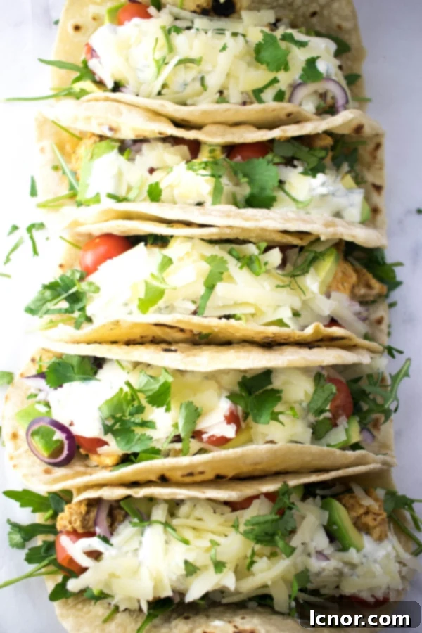 Sour cream, beyaz, kırmızı ve yeşil soslarla süslenmiş, tavukla doldurulmuş birkaç yumuşak taco