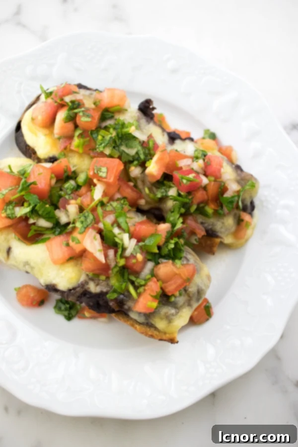 Delicious Cheesy Mexican Molletes 2 open faced cheese sandwiches topped with tomatoes and cilantro