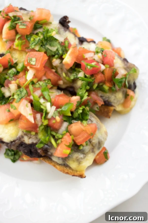 Delicious Cheesy Mexican Molletes 3 close up - open faced cheese sandwiches topped with tomatoes and cilantro