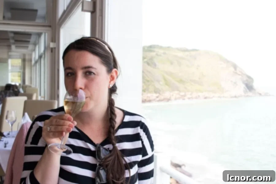 Woman enjoying a glass of Champagne with the stunning ocean and cliff view at La Sirene Restaurant in Cap Gris Nez, embodying coastal luxury.