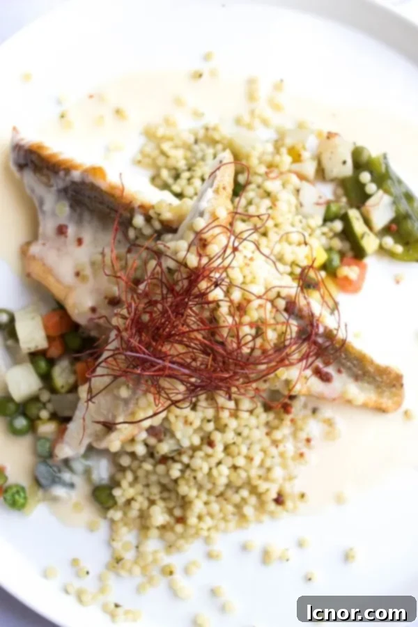 Elegantly plated red mullet fish, served atop a colorful medley of fresh vegetables and garnished with quinoa, a highlight of La Sirene's main courses.