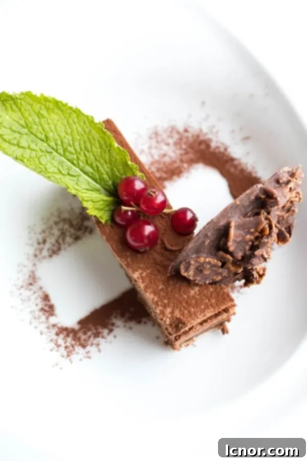 Decadent chocolate dessert with layers of crunch, topped with fresh red berries and a mint leaf, a beautiful creation from La Sirene Restaurant.