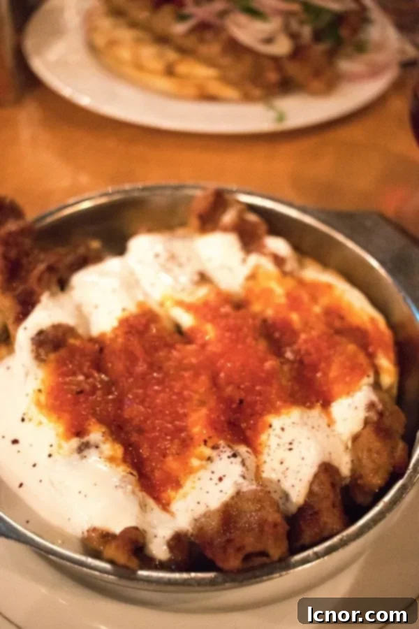 Lamb Souvlaki skewers topped with yogurt and tomato sauce.