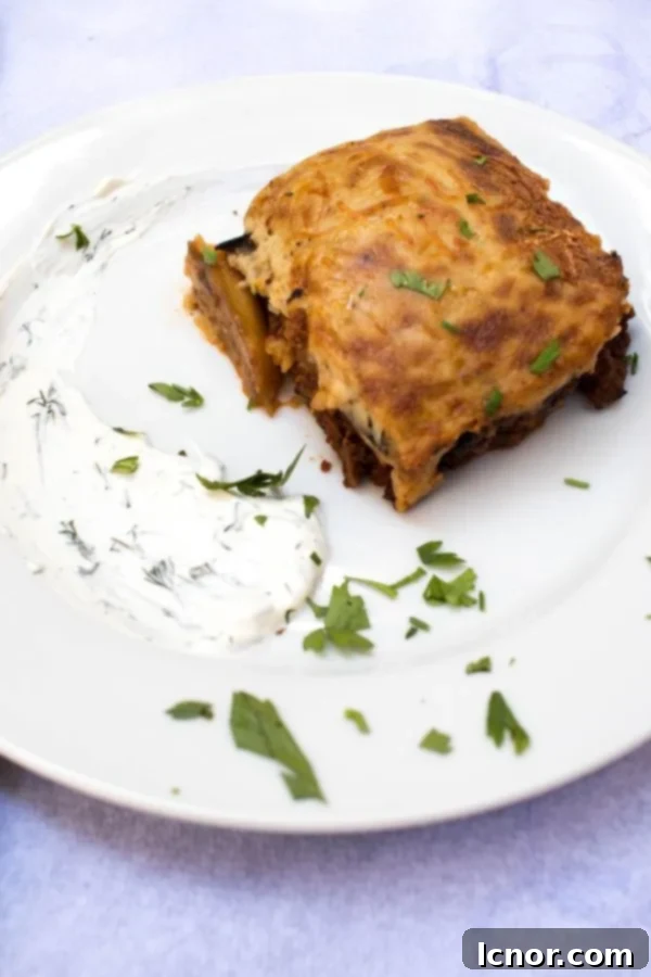 Slice of moussaka, a traditional Athens food, meat with mashed potatoes and topped with Bechamel sauce on a plate.