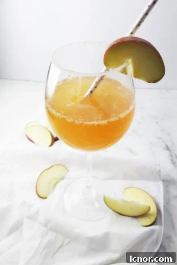 A simple yet elegant apple cider cocktail infused with apple, lemon, and ginger, served in a tall wine glass.