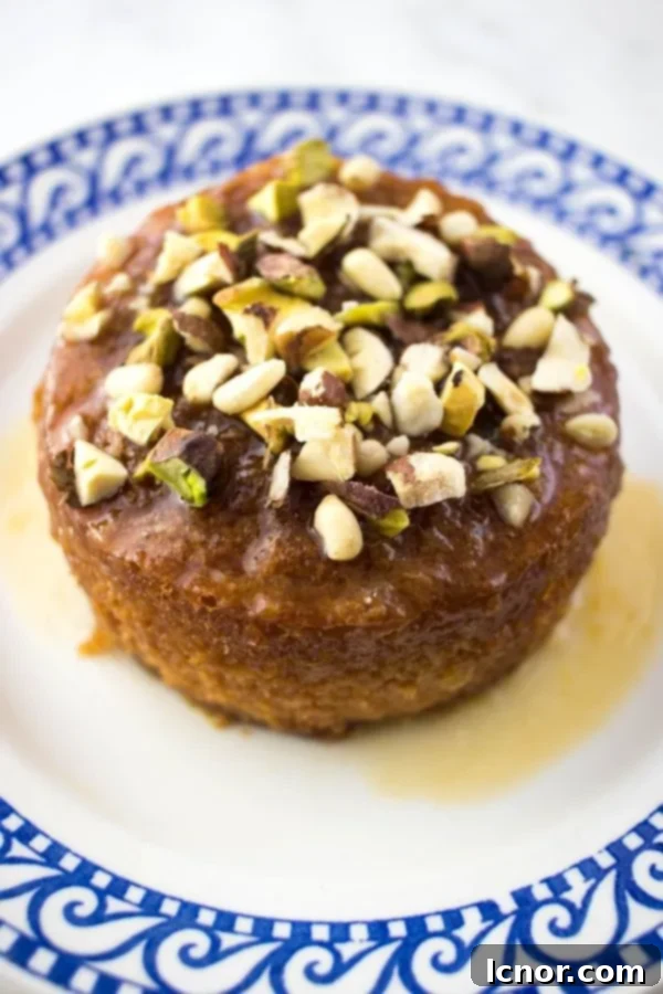 A beautifully sliced Tunisian orange cake topped with pistachios on a small blue & white plate, ready to be enjoyed.