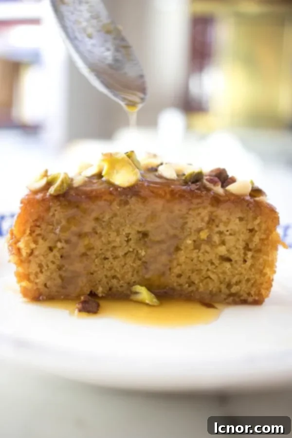 Close-up of a spoon drizzling vibrant citrus syrup over a freshly baked Tunisian orange cake, enhancing its moisture and flavor.