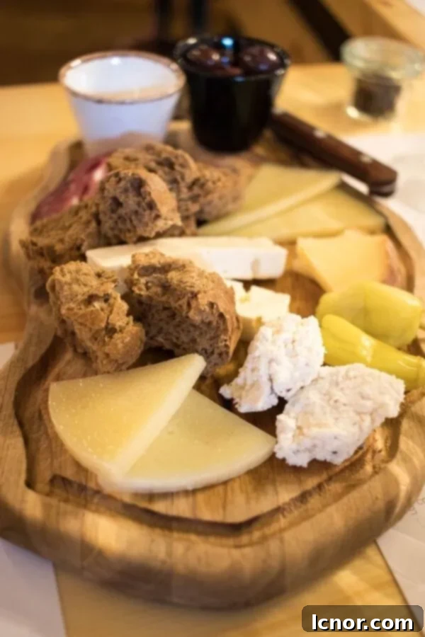 Wine tasting in Athens - a beautifully arranged selection of Greek cheeses, cold cuts & olives with fresh bread on a rustic wooden cutting board.